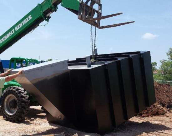 An underground bunker being lowered into the ground with a crane.