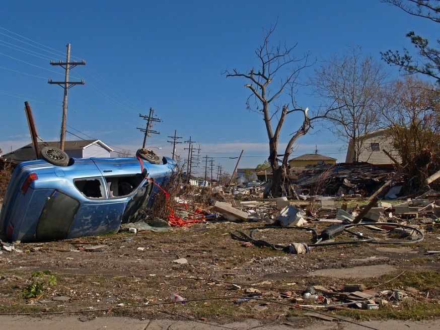 An upturned car and destruction and debris after a storm