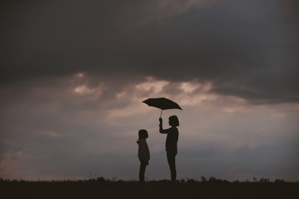 A woman holding an umbrella for her daughter
