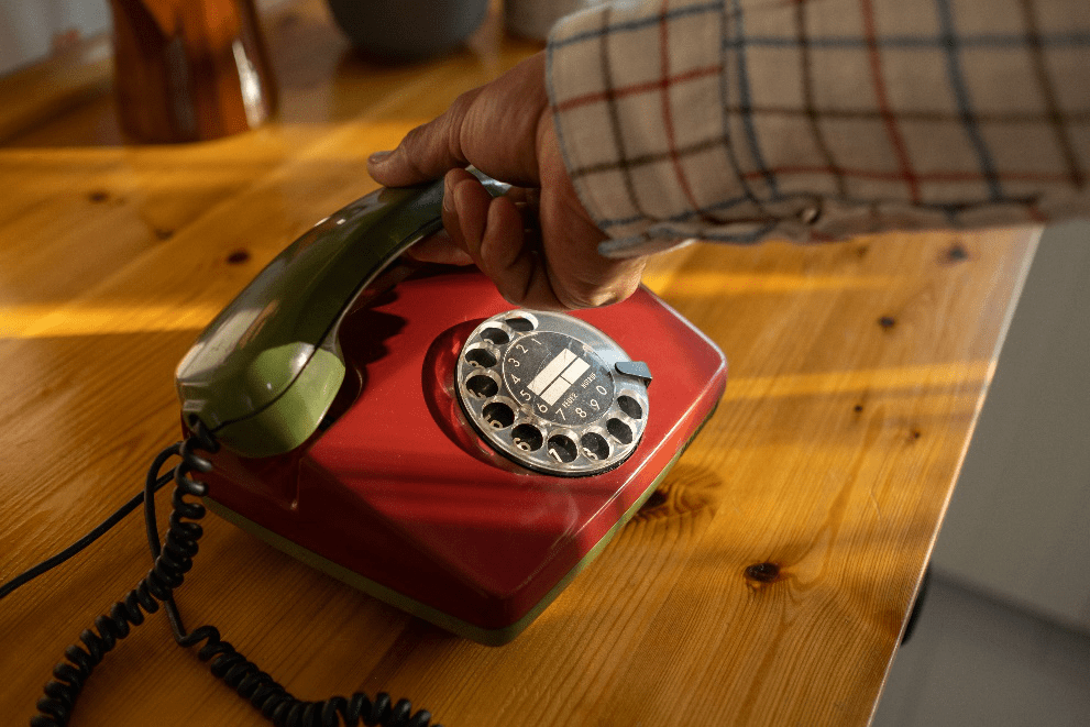 a man's hand reaching for the receiver on a landline phone