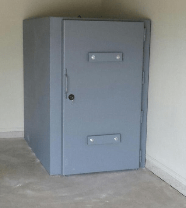 Steel safe room interior with reinforced walls, secure door, and built-in shelves for storage.