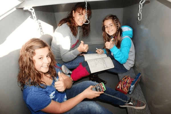 Women and kids sitting safely inside a garage storm shelter.