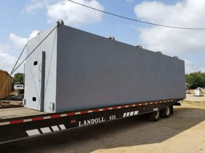A truck carrying a grey safety room.