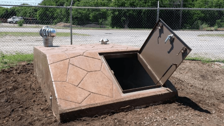 An image of a concrete underground tornado shelter with an open door