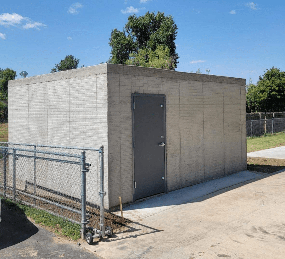 A sturdy above-ground cement shelter with a steel door placed outside a home in the backyard