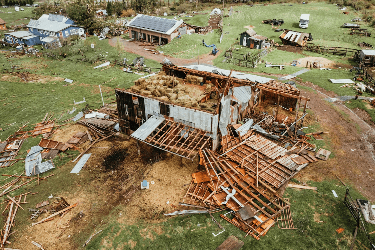 Aerial view of a house with major roof damage and debris scattered, showing the aftermath of a severe storm