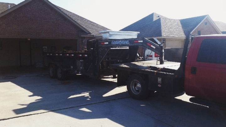 A large garage storm shelter being delivered inside a residential garage using a big truck and equipment