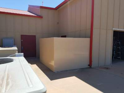 A tan safe room attached to the side of a house
