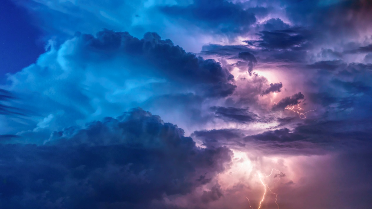 Intense lightning bolts illuminate dark storm clouds during a thunderstorm
