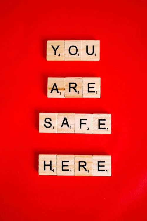 Wooden blocks spelling out the words “You Are Safe Here” on a red background.