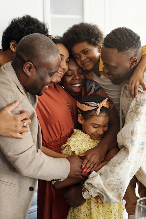 Family sharing a group hug indoors.