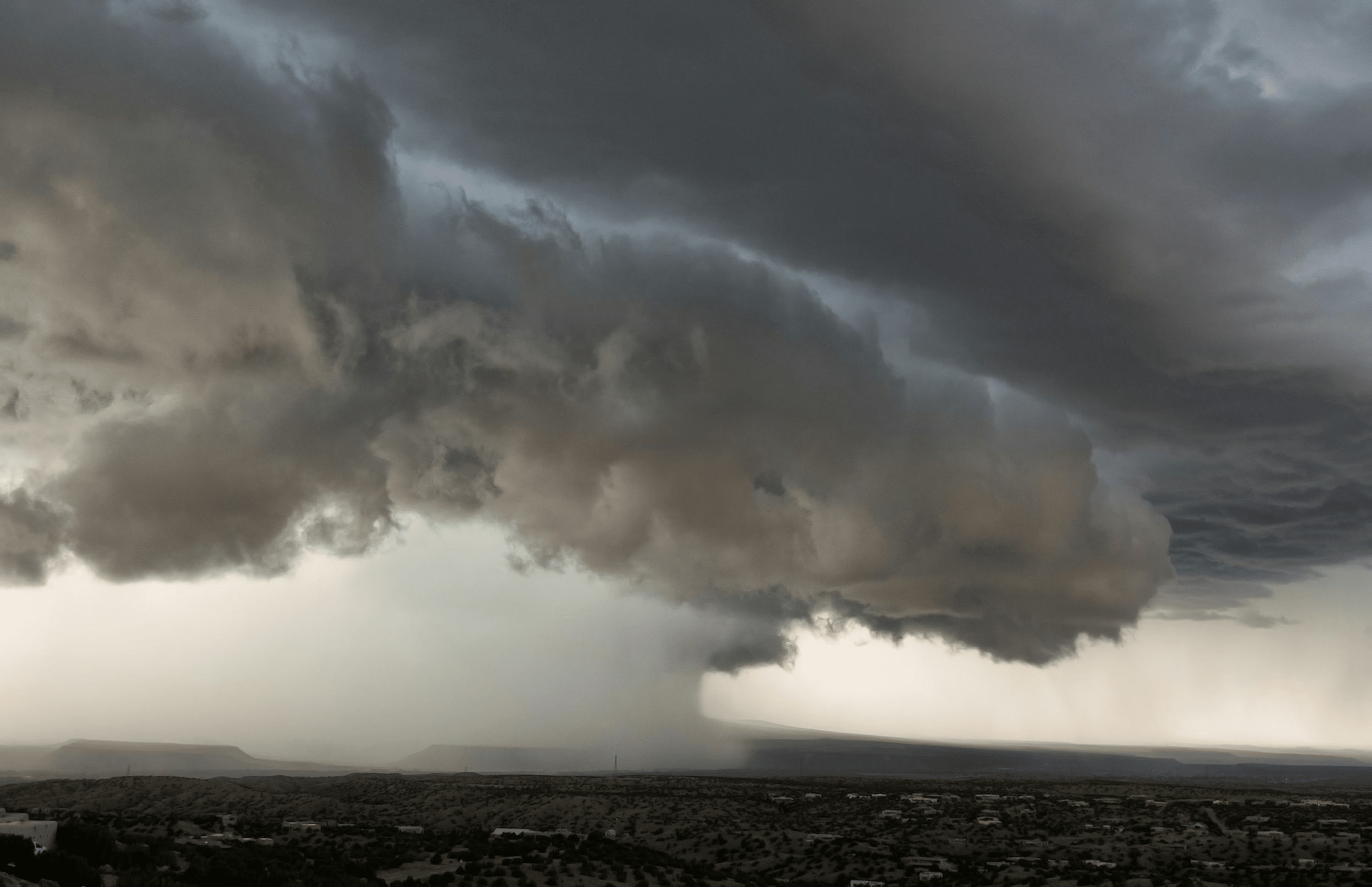 Dramatic tornado funnel forming over rural landscape
