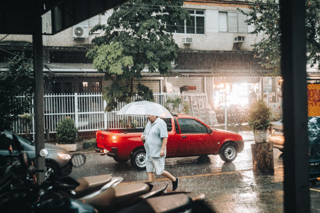 Person walking with an umbrella during heavy rain on a city street