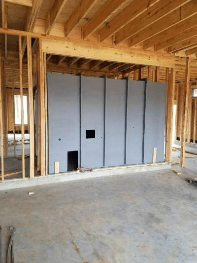 Reinforced interior safe room wall system installed inside residential wood framing during construction.