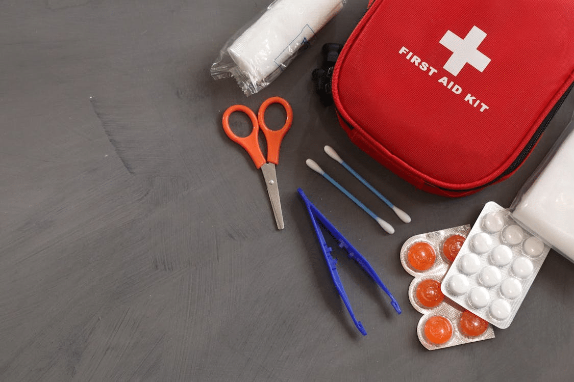 First aid kit with medical supplies, including scissors, bandages, and medications for storm shelter preparedness.