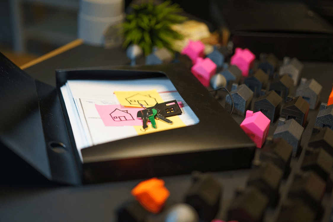 Miniature house models, keys, and real estate documents arranged on a desk