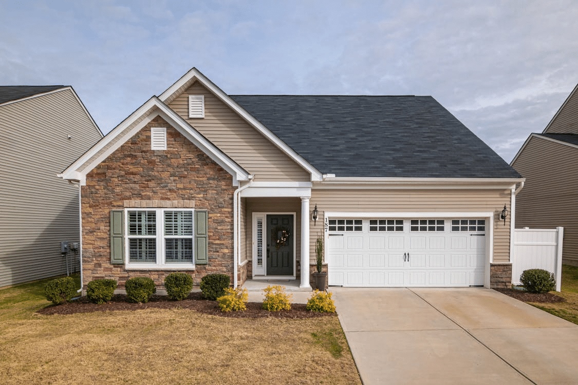 Traditional single-family home with a gabled roof, garage, and landscaped front yard