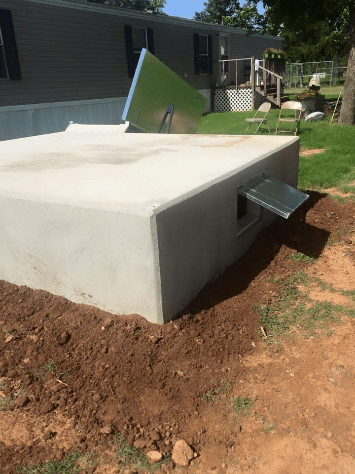 A picture shows a concrete storm shelter, partially buried in dirt, with a small metal vent.