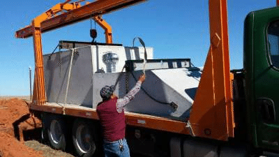Crew unloading a concrete storm shelter from a truck during residential installation in Oklahoma