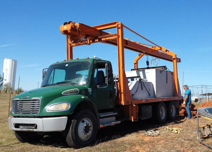 Storm shelter unit being delivered and lifted by crane truck.
