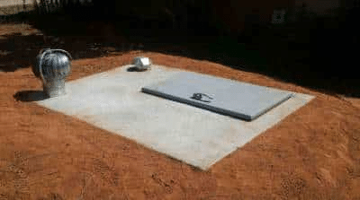 Outdoor concrete storm shelter with a closed steel hatch installed on a residential slab in Oklahoma