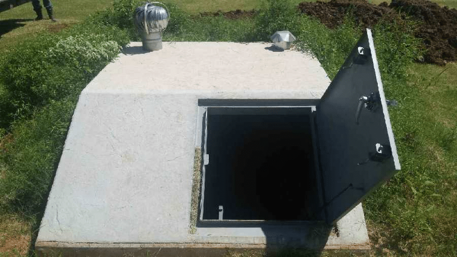 A picture shows an underground concrete storm shelter with its metal door open