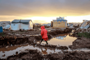 Unrecognizable girl walks over mud against shelter homes.