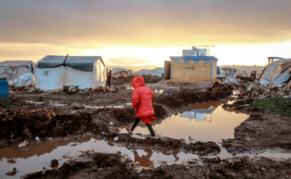 Unrecognizable girl walks over mud against shelter homes.