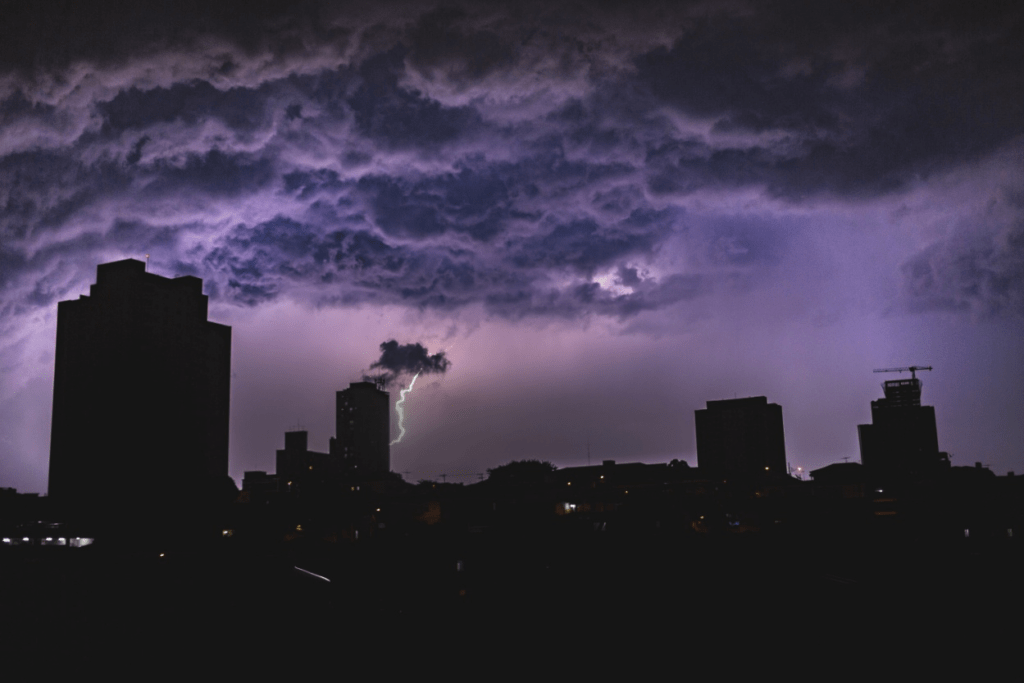 Heavy clouds and lightning formed over tall buildings.