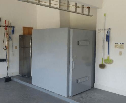A large grey metal safe room in a room.