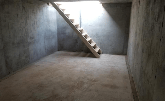 Inside of an underground cement shelter with a staircase.