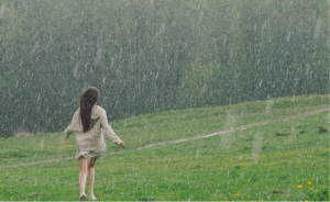 a woman enjoying rain in a grass field