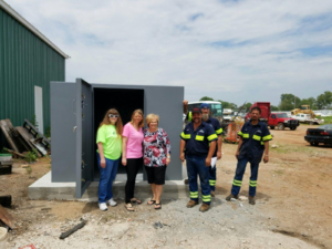 People standing next to a custom-made storm shelter.