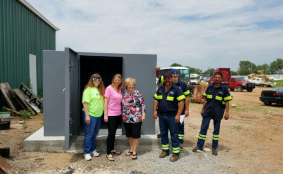 People standing next to a custom-made storm shelter.