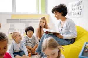 Female teacher reading a book to children