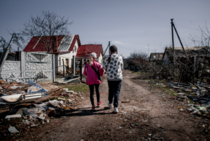 Two girls walking by the remains left behind by a tornado.